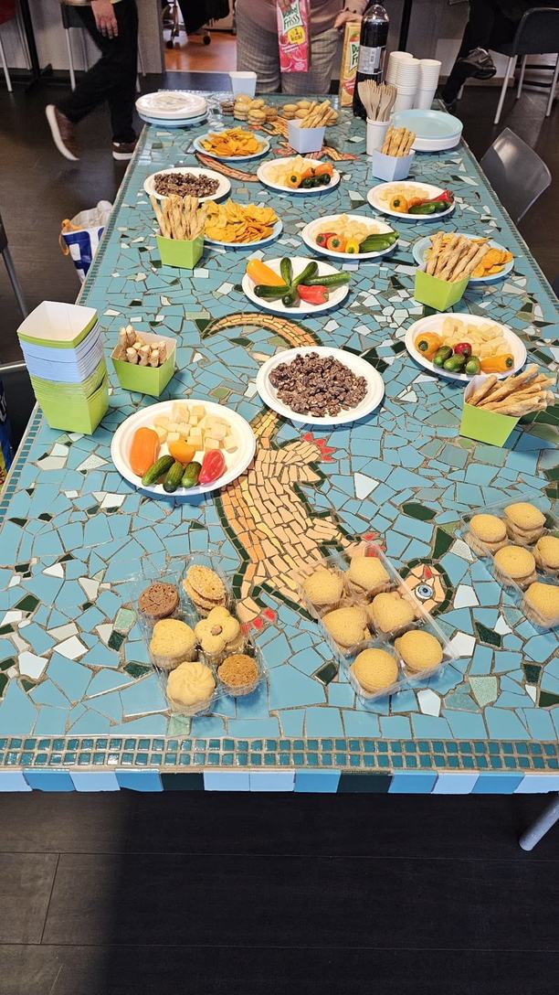 طاولة من الفسيفساء عليها أطباق خضار وجبن ورقائق بطاطس وأعواد خبز وبسكويت.